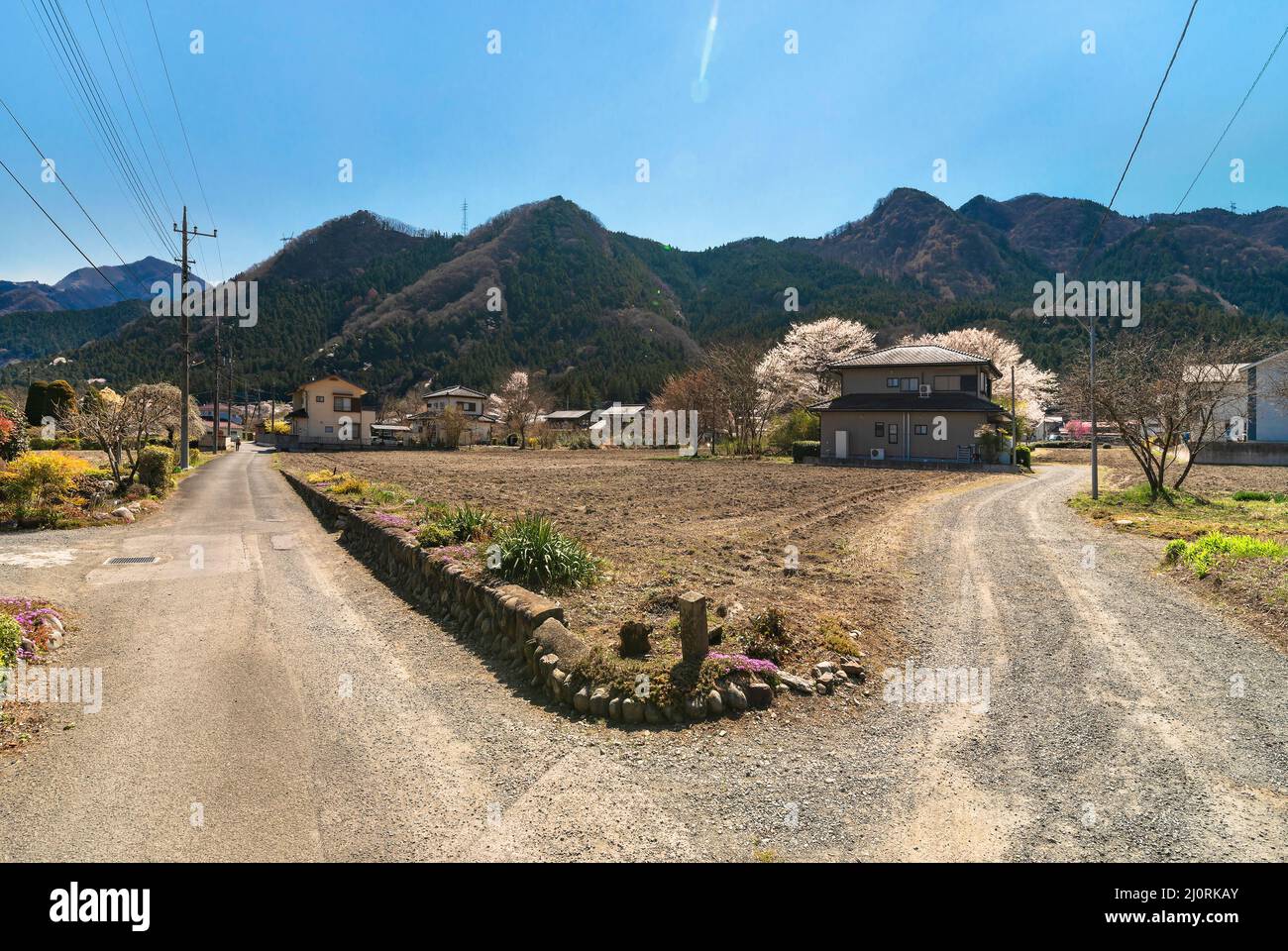 saitama, japan - march 20 2022: Road bifurcation in a Japanese countryside of Chichibu city with fallow crop fields and houses and the Bukō mountains Stock Photo
