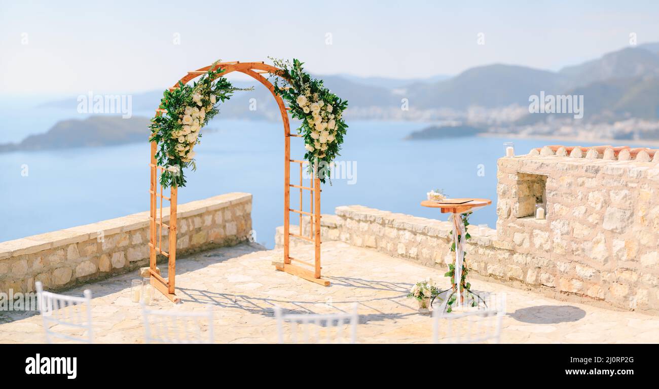 Wooden wedding arch decorated with flowers stands on the observation deck above the sea Stock Photo