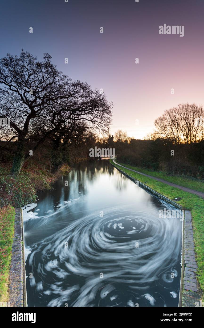 Siwrling water and tree reflections on the Staffordshire/Worcestershire canal at dawn on a frosty winter morning Stock Photo