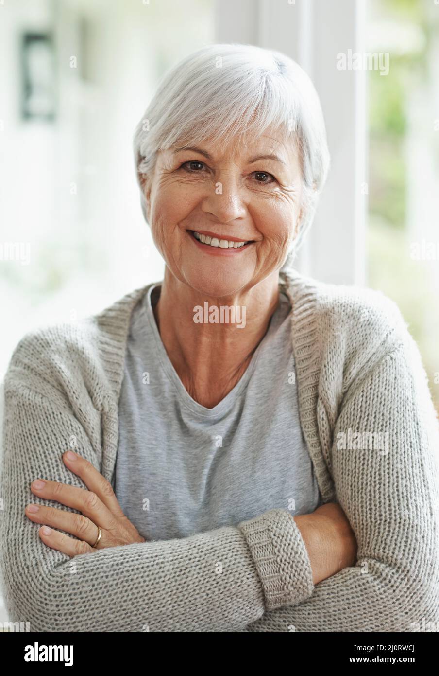 Happy in the knowledge that Ive planned for my retirement. A happy senior woman smiling at the camera as she sits in her home. Stock Photo