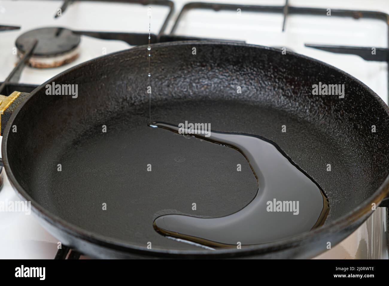 The process of pouring vegetable oil into a cast iron heated frying pan