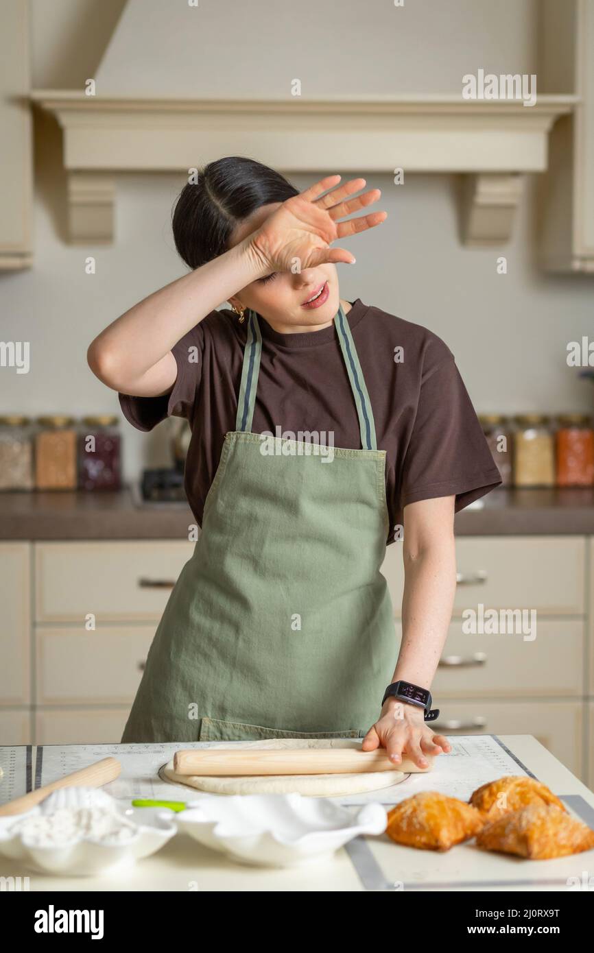 Tired housewife cook wipes sweat from her forehead in the kitchen. The