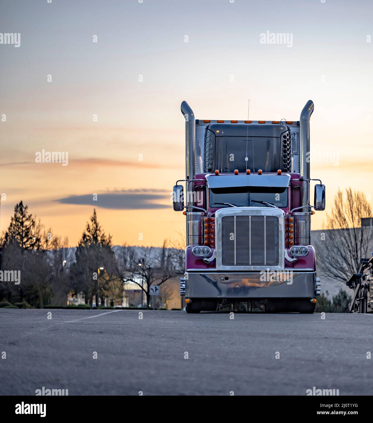 Burgundy stylish big rig American semi truck tractor with high chrome pipes and refrigerator semi trailer standing for the truck driver rest on wide p Stock Photo