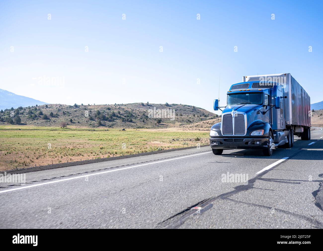 Classic long haul big rig blue semi truck with truck driver cab ...