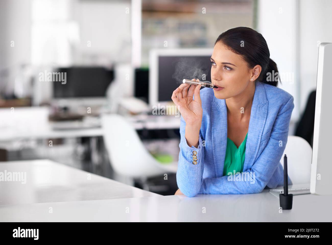Having a quick vape between meetings. Shot of a businesswoman smoking and  electronic cigarette in an office Stock Photo - Alamy