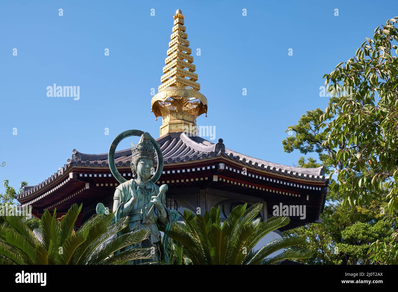 Kannon statue and the curved pagoda roof with golden sorin at Isshinji Temple. Tennoji. Osaka. Japan Stock Photo