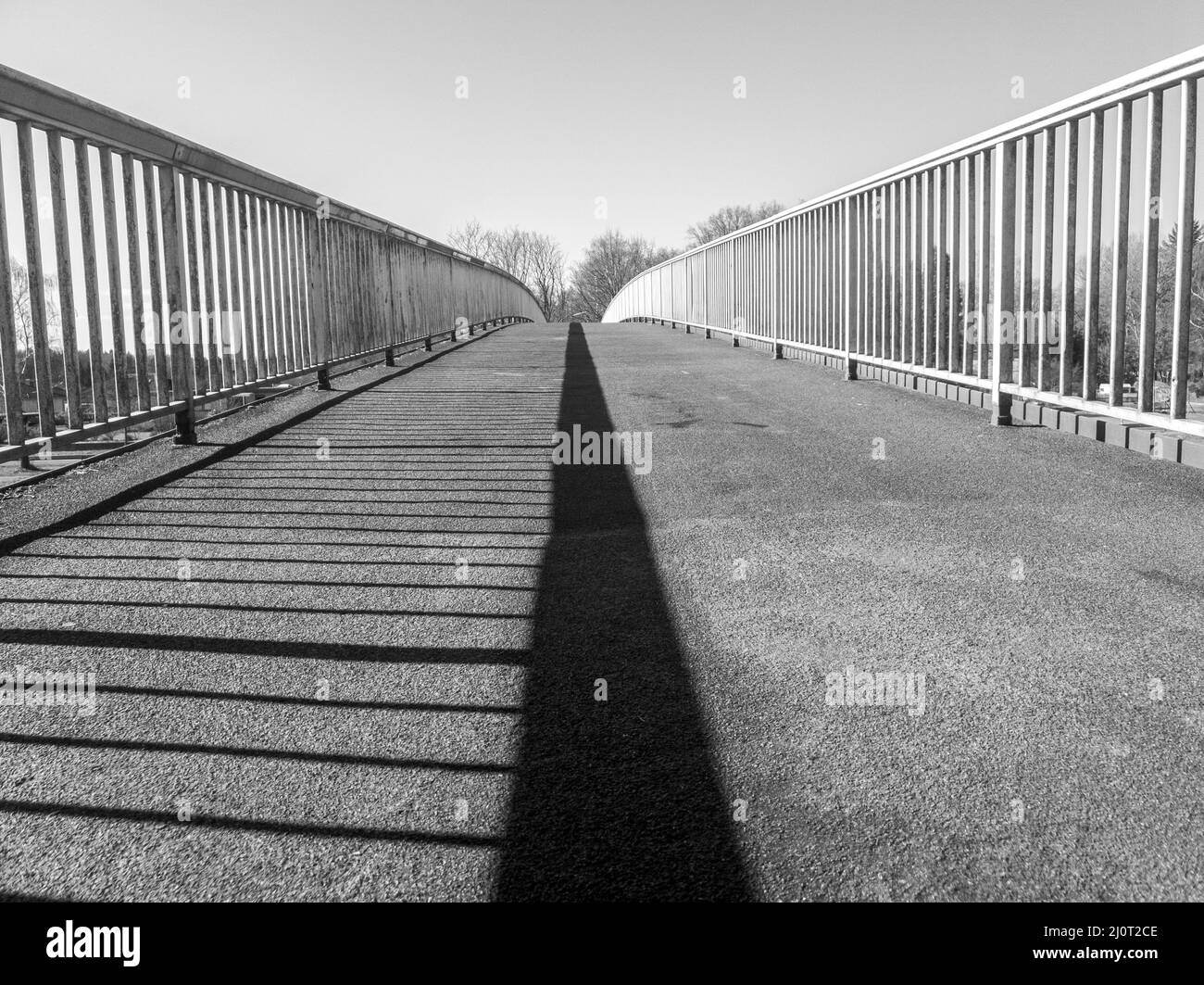 Bridge over a river, with the railing as a shadow in the middle. in black and white Stock Photo