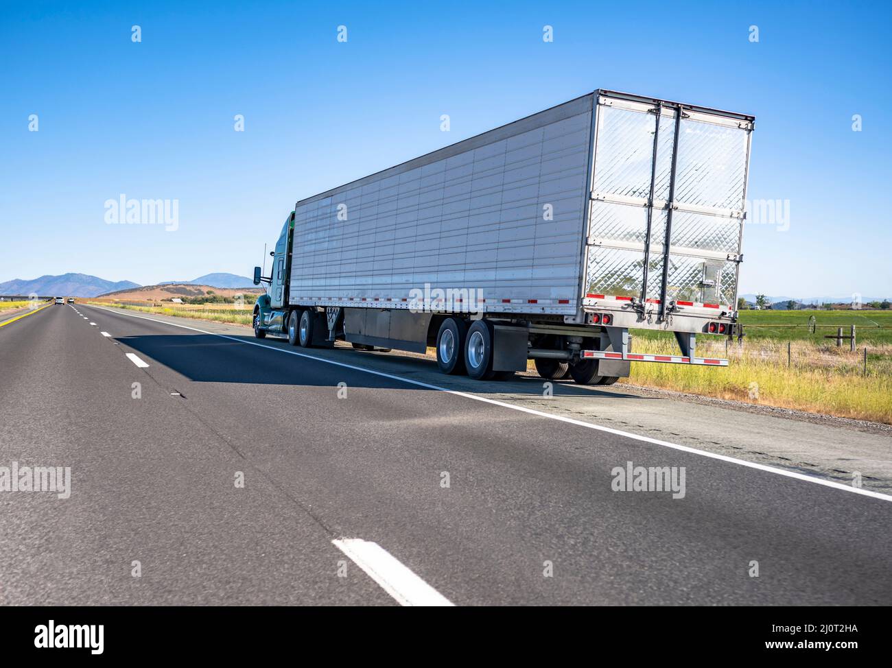 Broken green big rig semi truck with extended cab for long haul and refrigerator semi trailer standing out of service on the road shoulder in Washingt Stock Photo