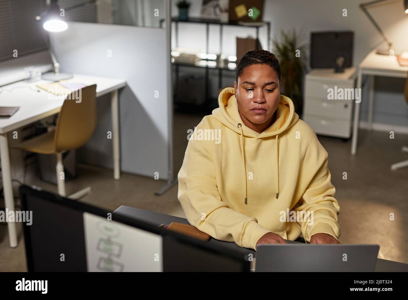 Portrait of female IT developer using computers while working in office at night, copy space Stock Photo