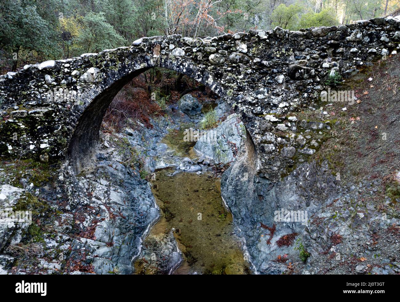 Aerial drone photograph of a medieval stoned bridge with water flowing in the river. Elia Bridge Troodos Cyprus Stock Photo