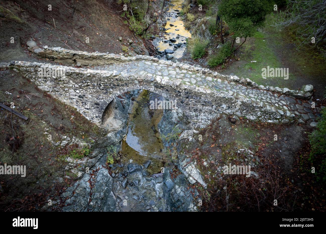 Aerial drone scenic of a medieval stoned bridge with water flowing in the river. Elia Bridge Troodos cyprus Stock Photo