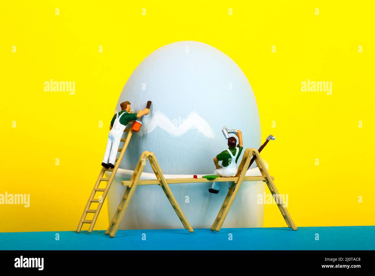Conceptual image of miniature figure people painting a hens egg for Easter Stock Photo