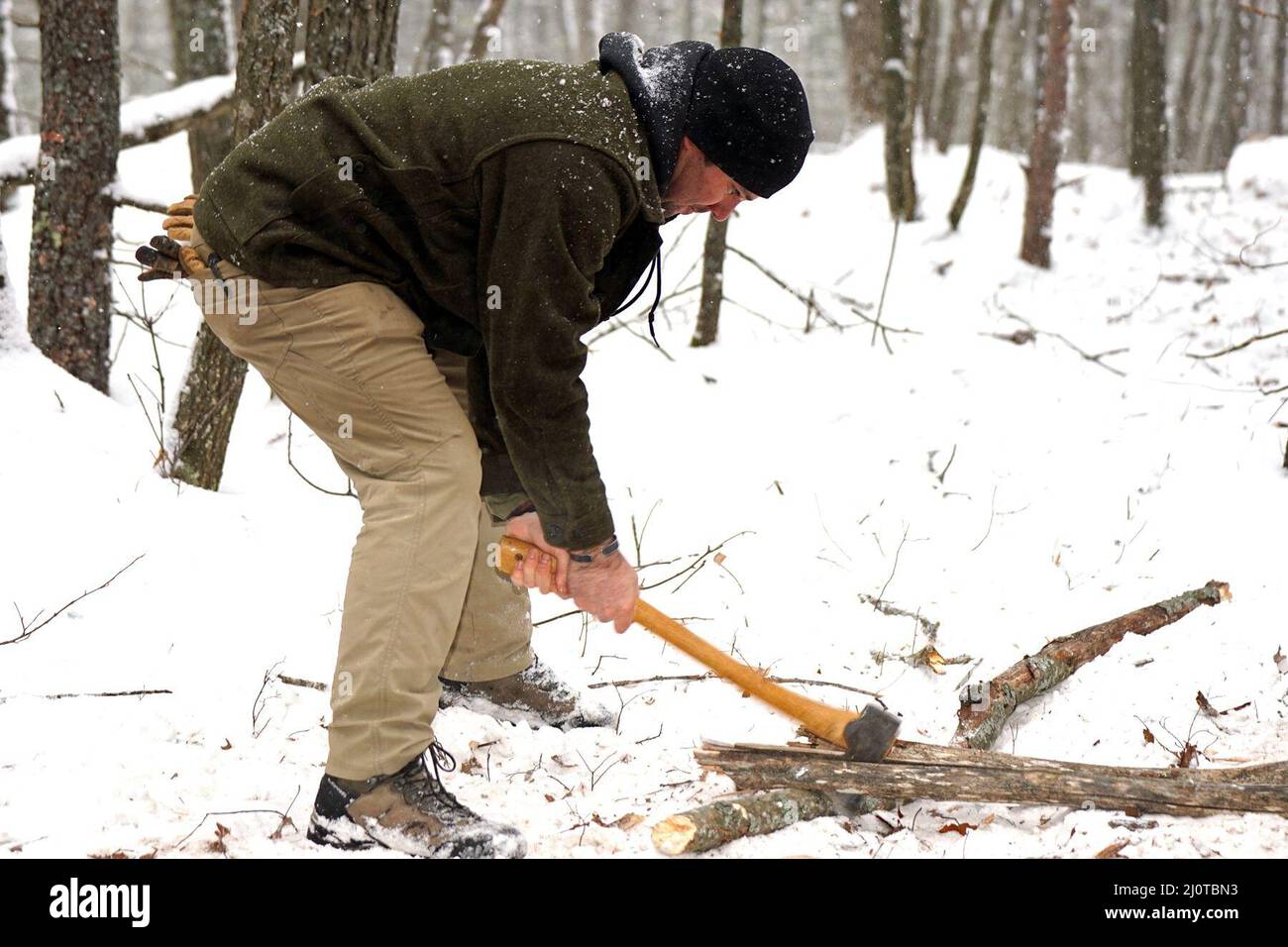 GRAYLING, Mich. – A U.S. Army Soldier and an instructor from the 720th Special Tactics Group, Hurlburt Field, Florida, chops wood to feed a fire for cold weather survival training during Northern Strike 22-1 on Jan. 22, 2022. “Winter Strike” is held annually in northern Michigan during the coldest part of the year. Snow, high winds, and single-digit temperatures are commonplace at the National All-Domain Warfighting Center this time of year. Visiting units are able to train in subarctic conditions, so they are better able to meet the objectives laid out in the Department of Defense’s Arctic st Stock Photo