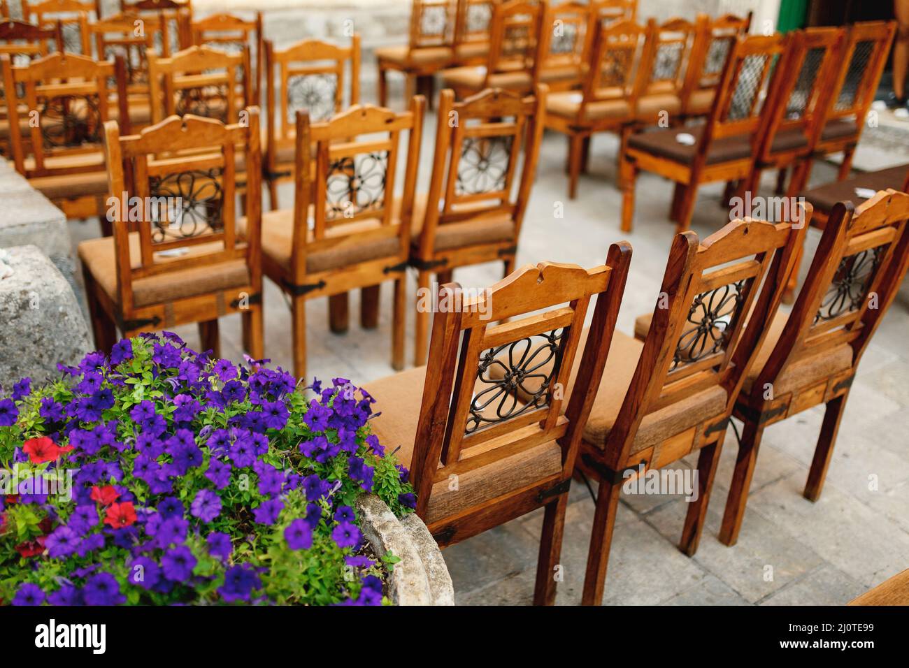 Wooden chairs with patterns on the backs stand in rows on paving stones Stock Photo
