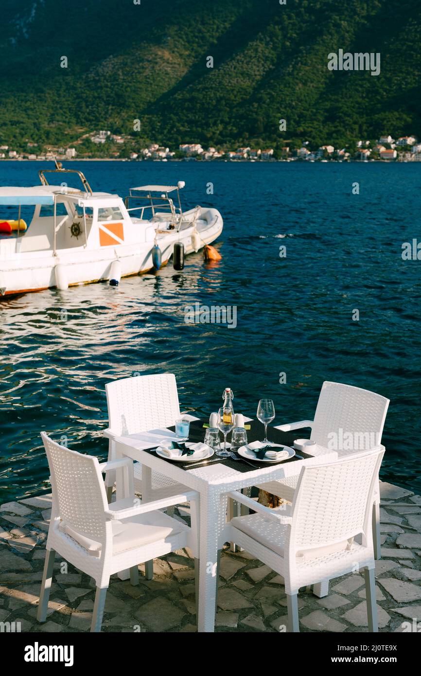 Laid festive table with chairs stands on the pier by the sea Stock Photo