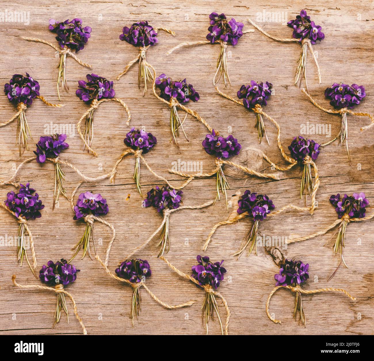 Little bunches of wild flowers and violets on old wooden background, top view flat lay Stock Photo