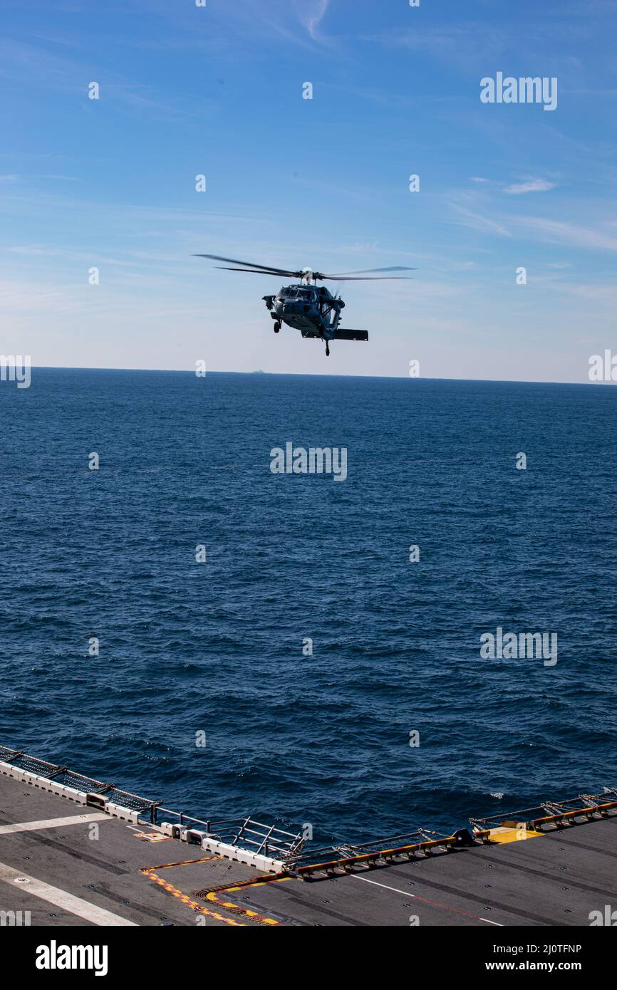 A U.S. Navy MH-60 Seahawk conducts flight operations during Composite Training Unit Exercise (COMPTUEX) aboard the USS Kearsarge (LHD 3), Jan. 24, 2022. The 22nd Marine Expeditionary Unit and Amphibious Squadron (PHIBRON) Six are underway for COMPTUEX in preparation for an upcomingdeployment. COMPTUEX is the last at-sea period in the MEU’s Predeployment Training Program; it aims to test the capabilities of the ARG/MEU and achieve deployment certification. (U.S. Marine Corps photo by Sgt. Armando Elizalde) Stock Photo