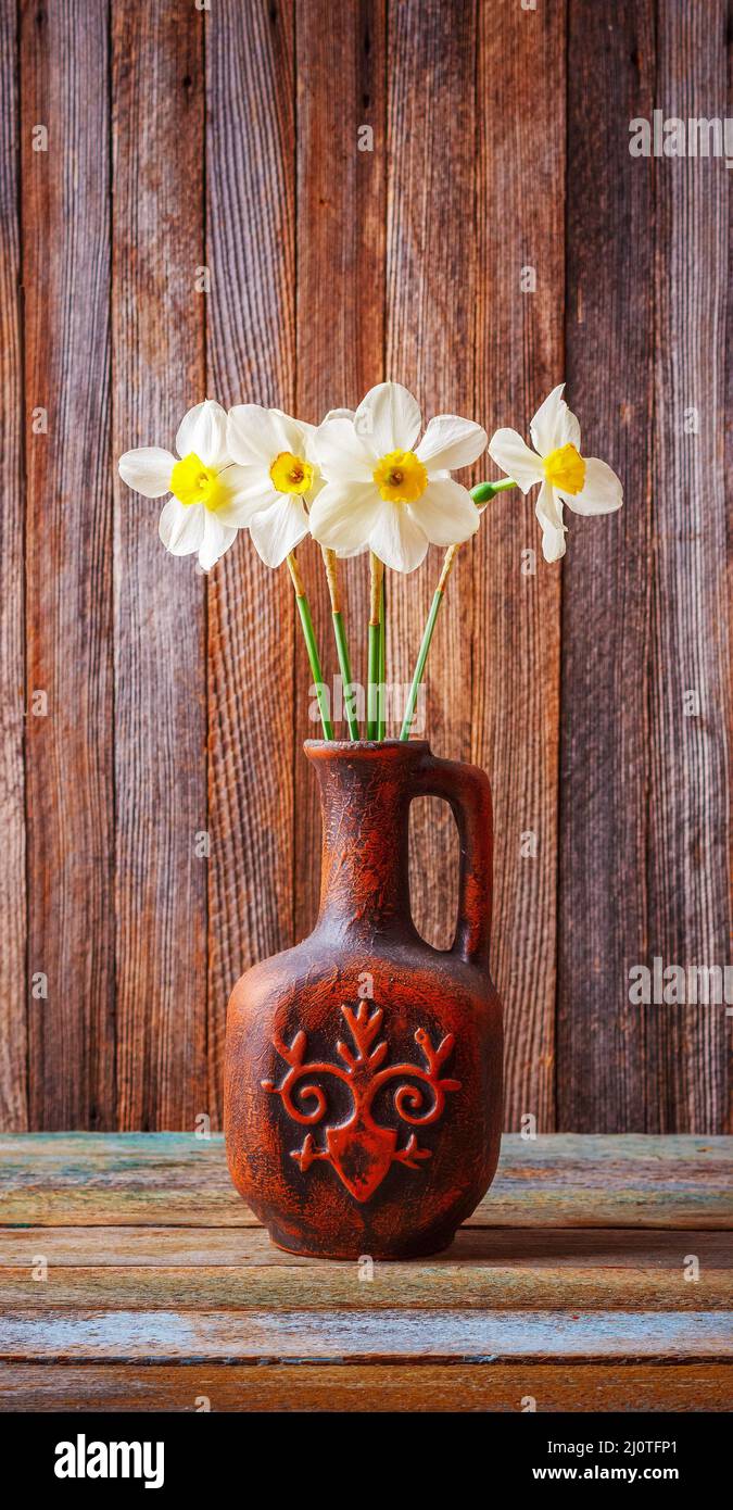 Still life of a bouquet of daffodils flowers in an old ceramic jug on a ...
