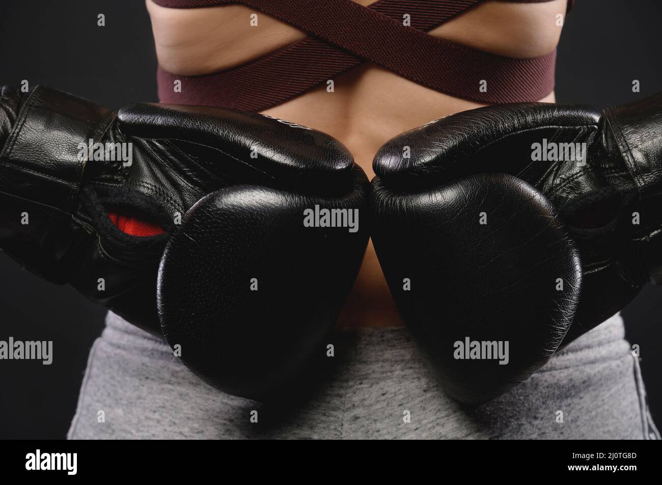 Close-up from the back of the hand of a woman athlete in black boxing gloves. Concept of woman strength and female wrestling Stock Photo