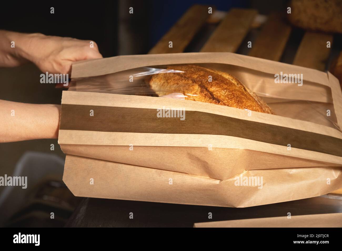 A loaf of white artisan hot bread in a paper bag with transparent ...