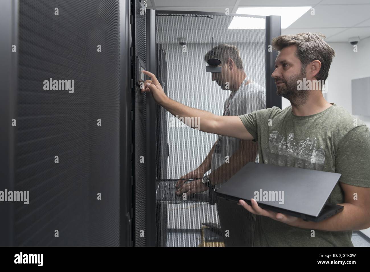 Technicians team updating hardware inspecting system performance in super computer server room or cryptocurrency mining farm. Stock Photo