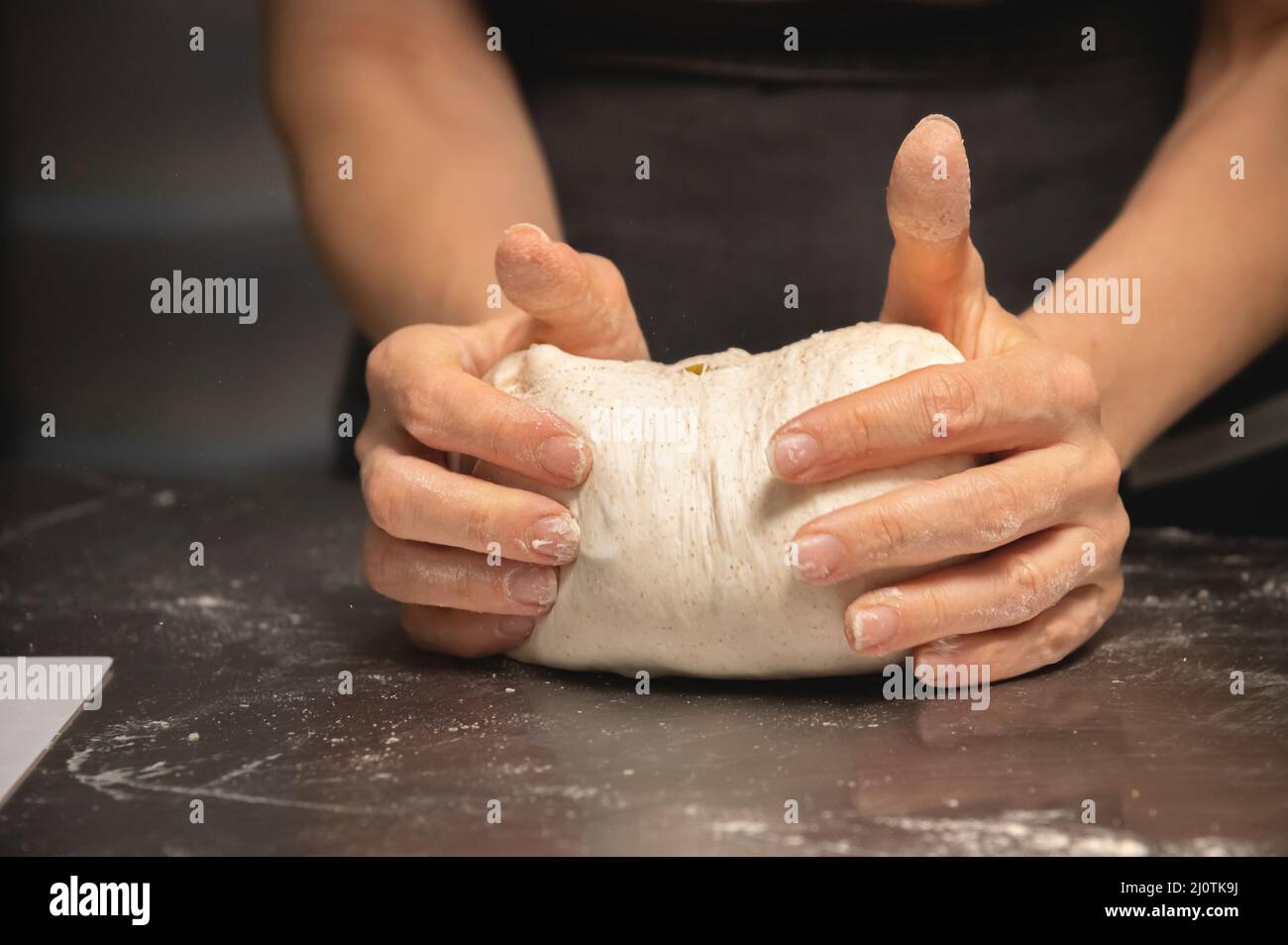 Close-up of female hands kneading dough for making artisan bread at home bakery Stock Photo