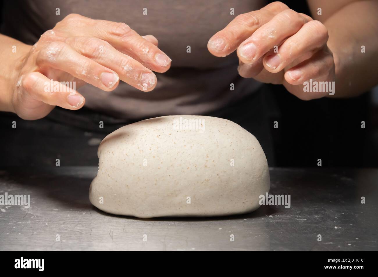 Close-up of female hands kneading dough for making artisan bread at home bakery Stock Photo