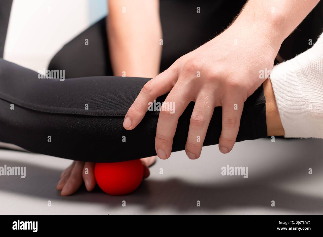 Physiotherapist teaches self-massage with red balls, patient with leg injury. Treatment of sports injuries. Practical use. Rehab Stock Photo