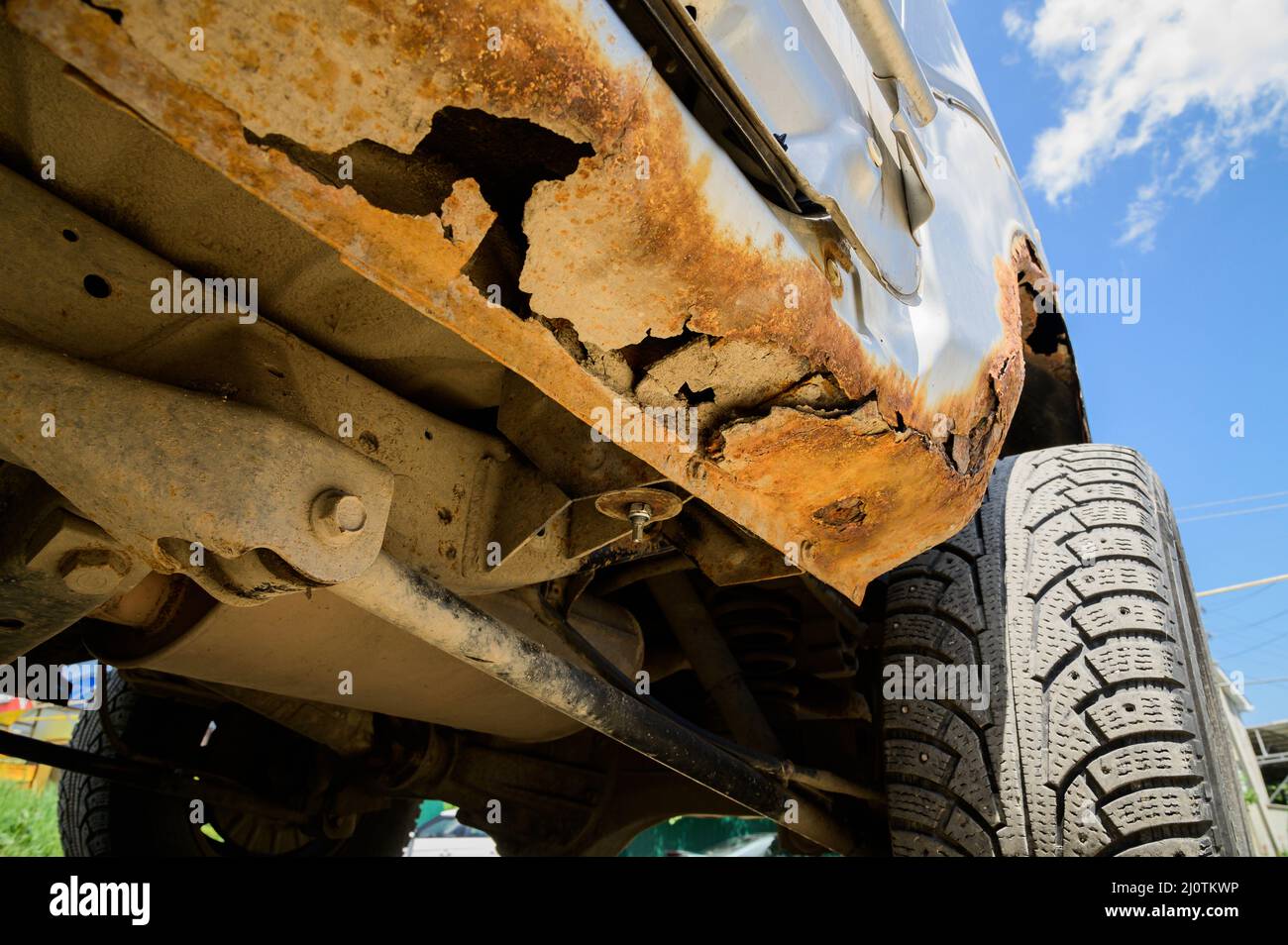 Rusty part of the car body with throughout corrosion. Background for