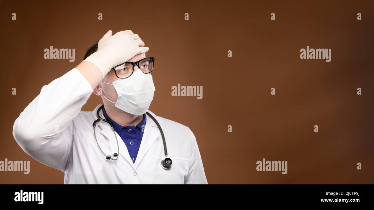 Panoramic Young caucasian doctor in a medical uniform makes a facepalm gesture. Medical errors and stupidity Stock Photo