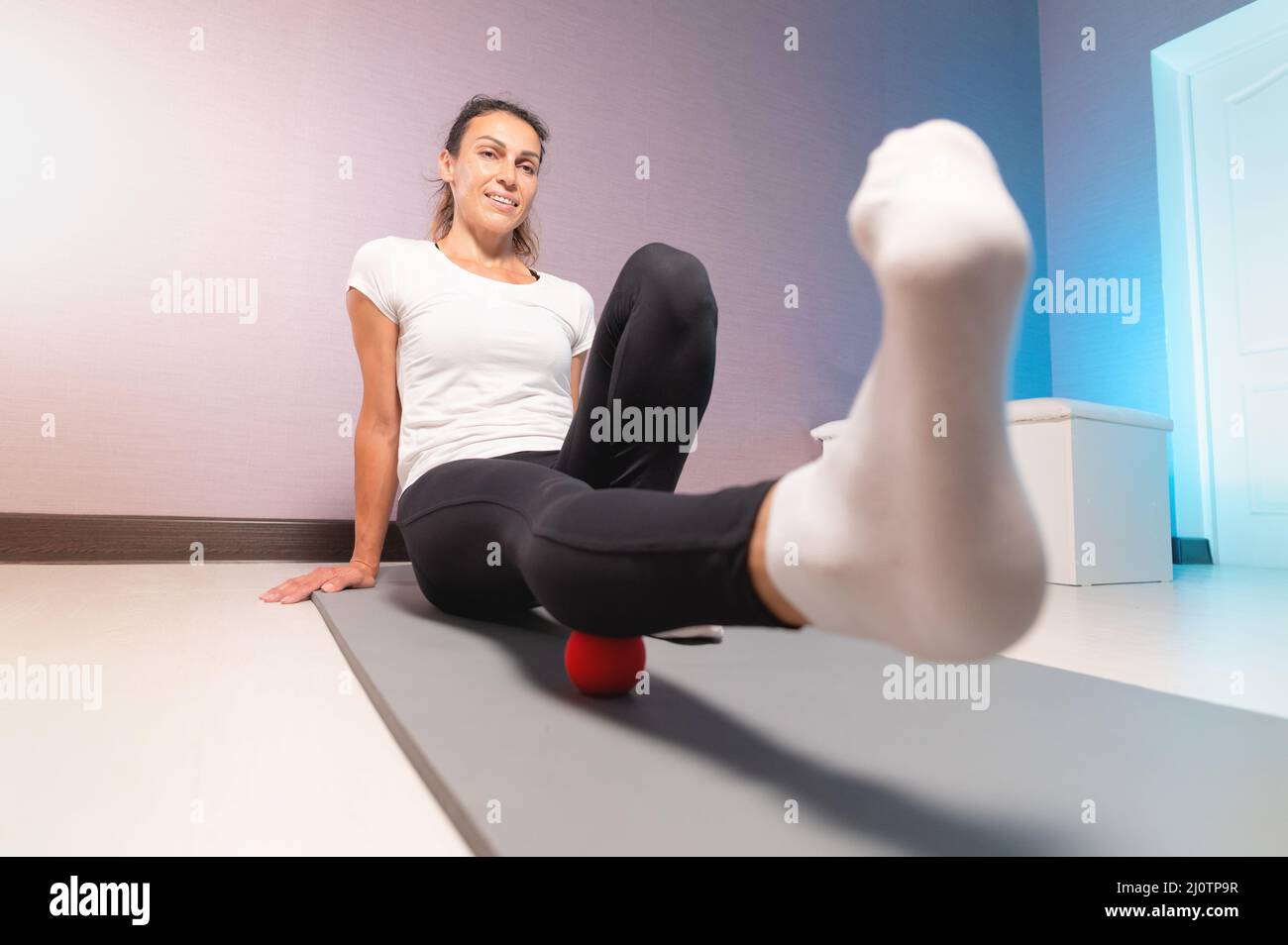 Caucasian woman doing myofascial massage with a massage ball. Myofasceal massage of thighs and gluteal muscles Stock Photo