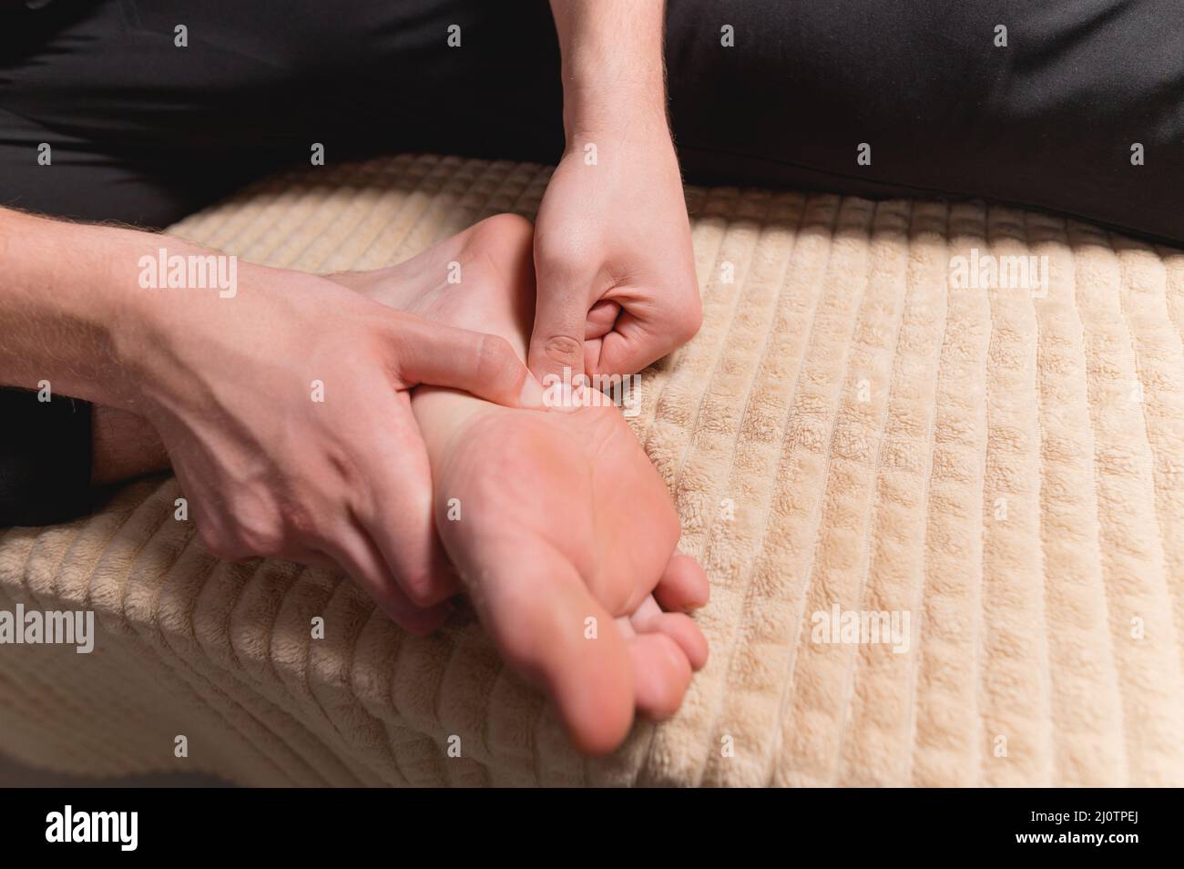 Caucasian man doing self-massage of the foot and the surface of the leg. Prevention of flat feet and caring for your body Stock Photo