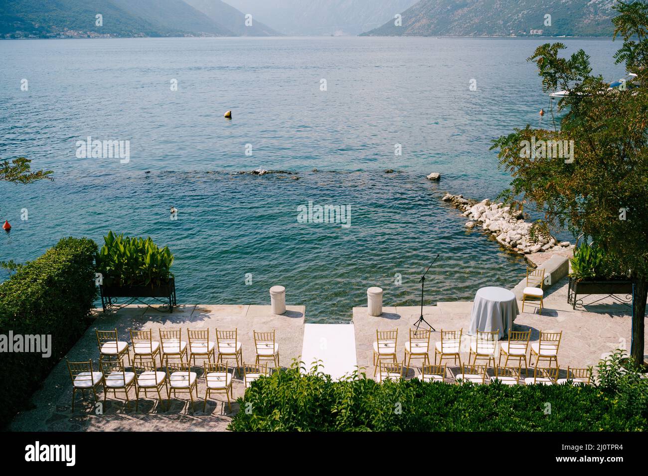 Rows of white chairs stand on the pier next to the registration desk by the water Stock Photo