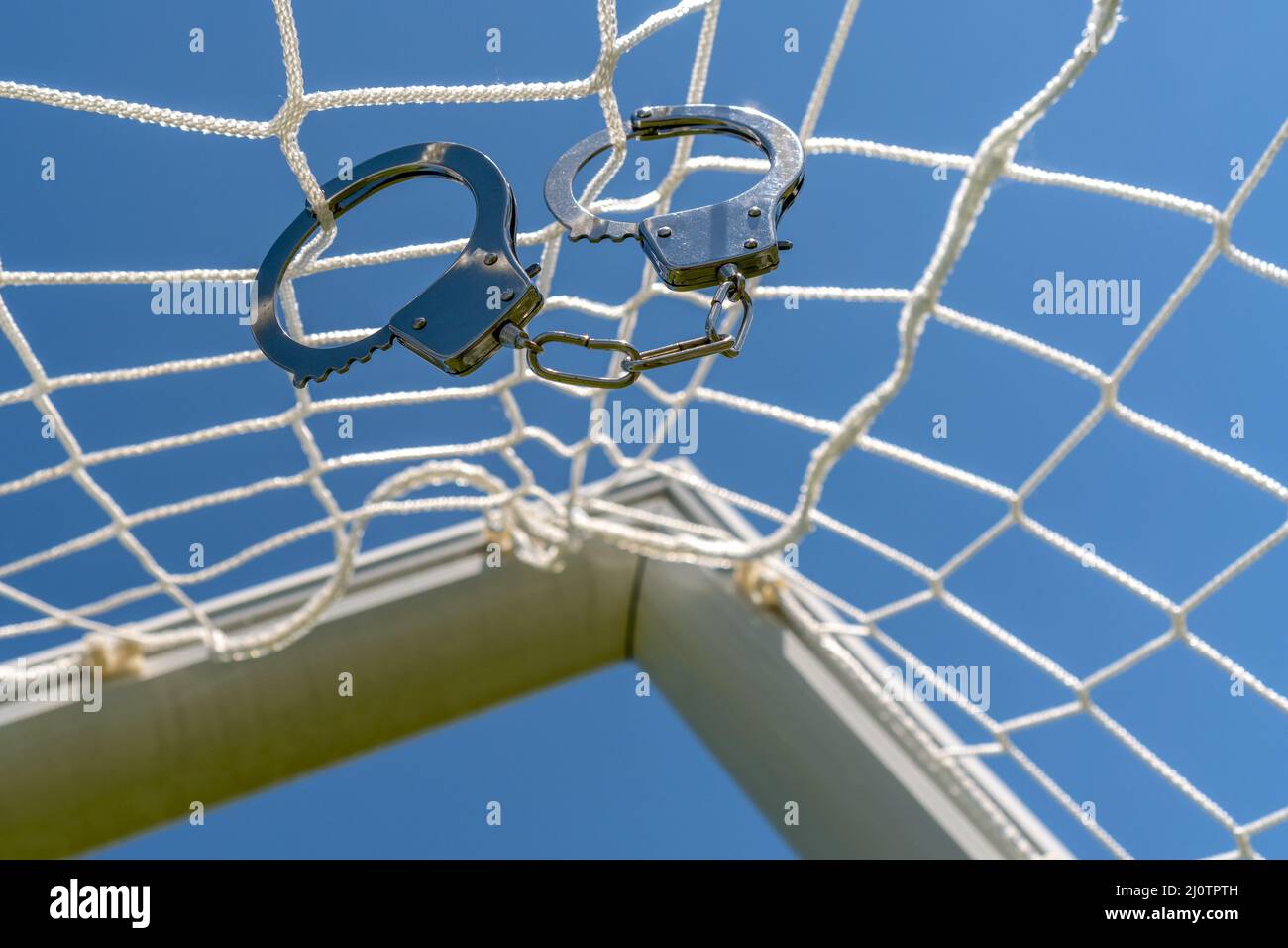Handcuffs hanging on the net of a football goals Stock Photo