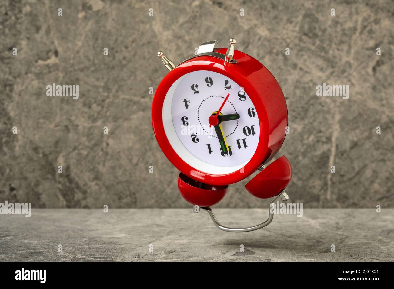 Red alarm clock falling on the stone background Stock Photo Alamy