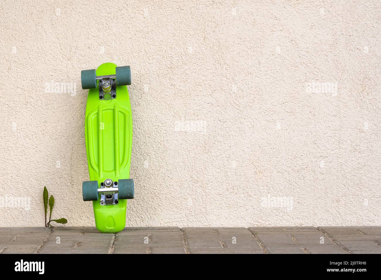 Green skateboard leaning against white wall Stock Photo Alamy