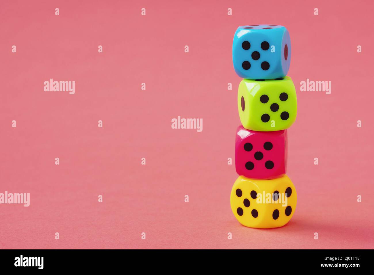 Stack of colorful dice on pink background Stock Photo