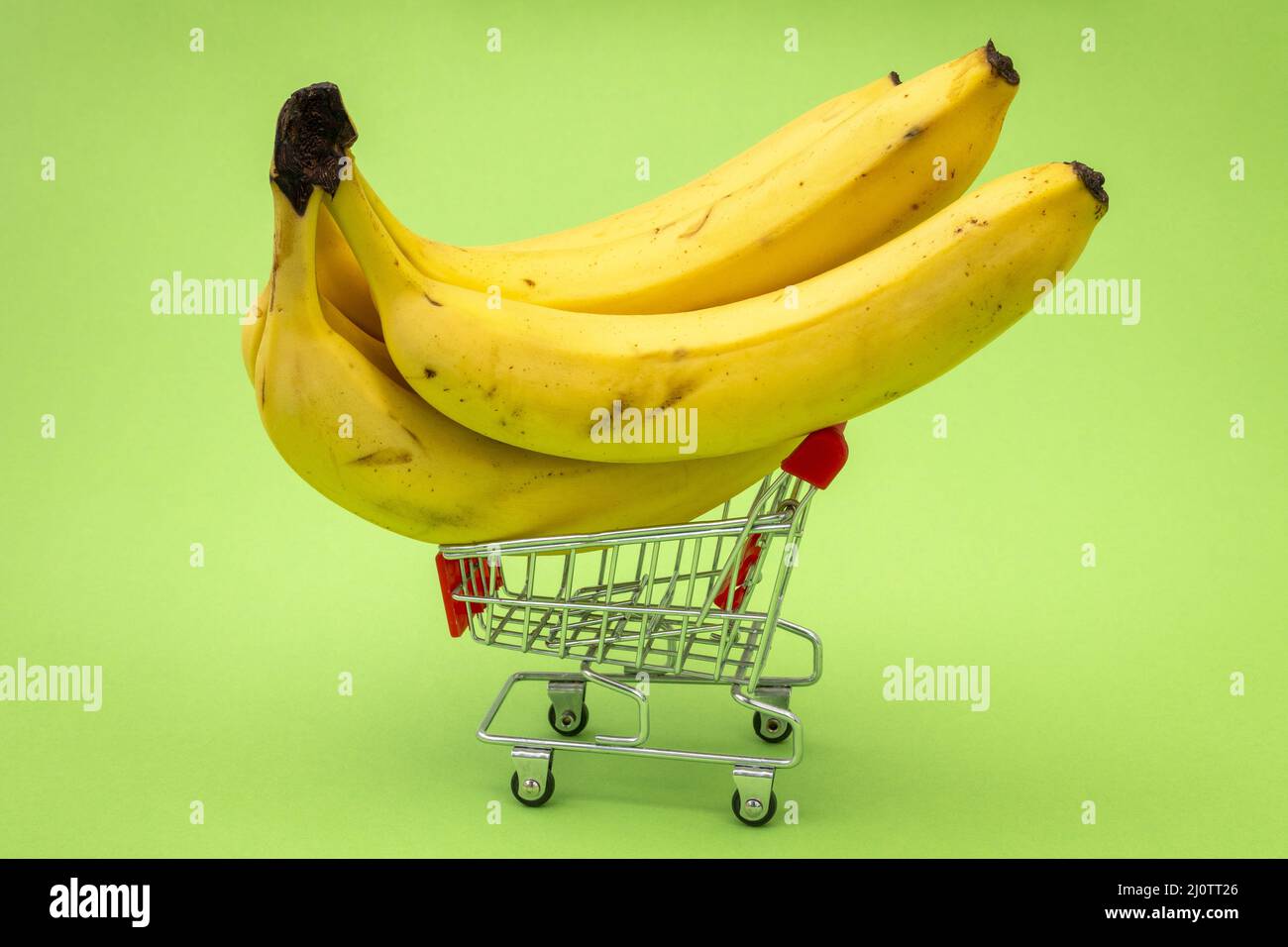 Shopping trolley full of bananas on green background Stock Photo - Alamy