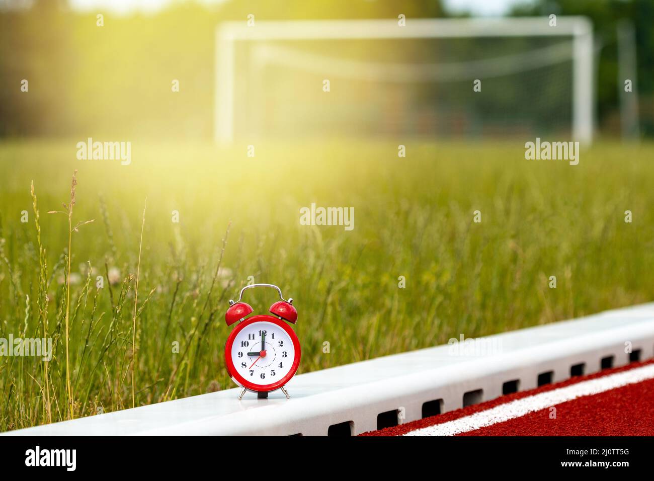 Red alarm clock on the football field Stock Photo