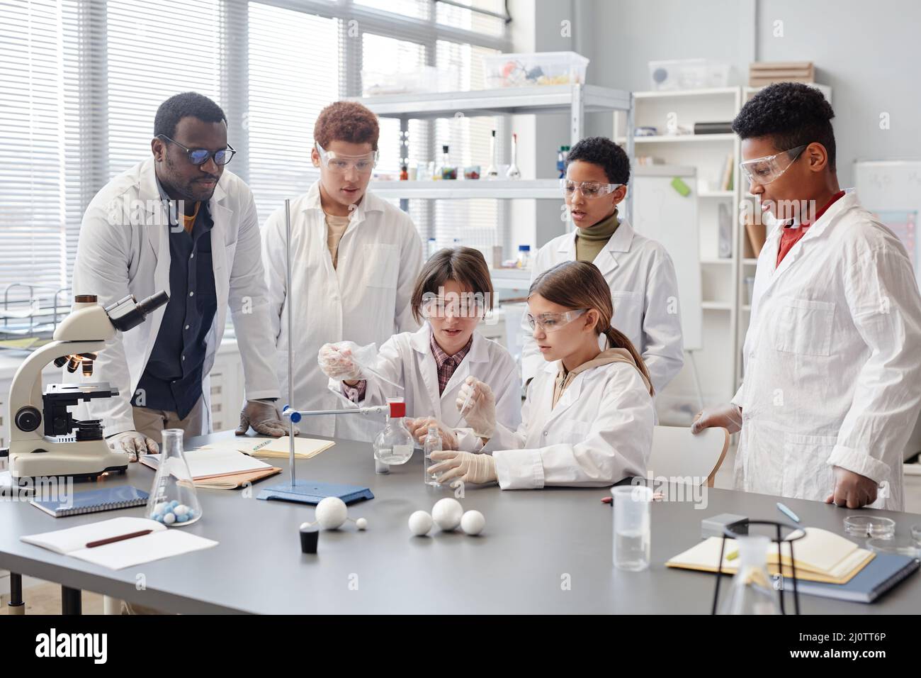 Large group of diverse children wearing lab coats in chemistry class