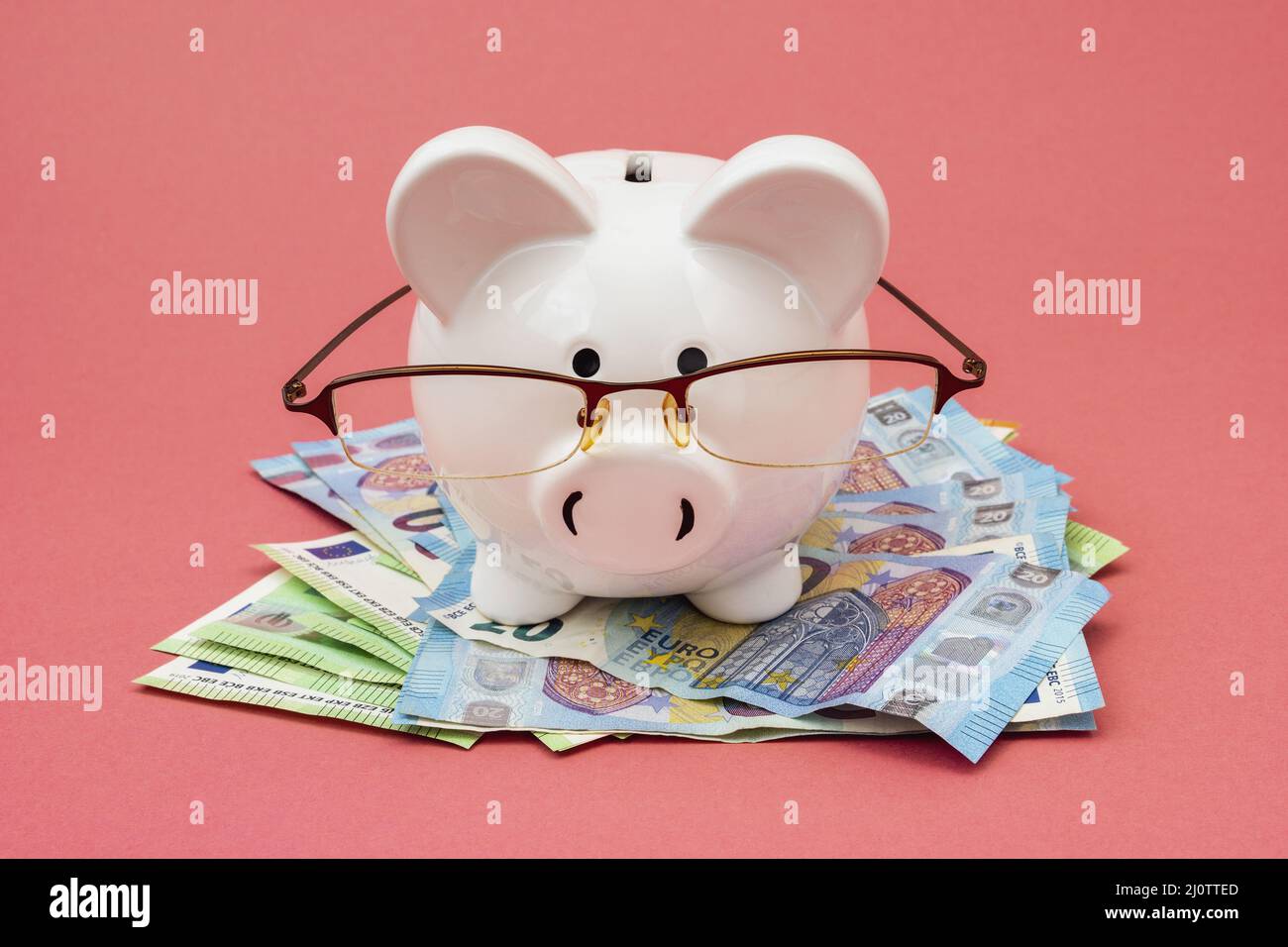 Piggy bank wear glasses standing on a pile of cash Stock Photo - Alamy