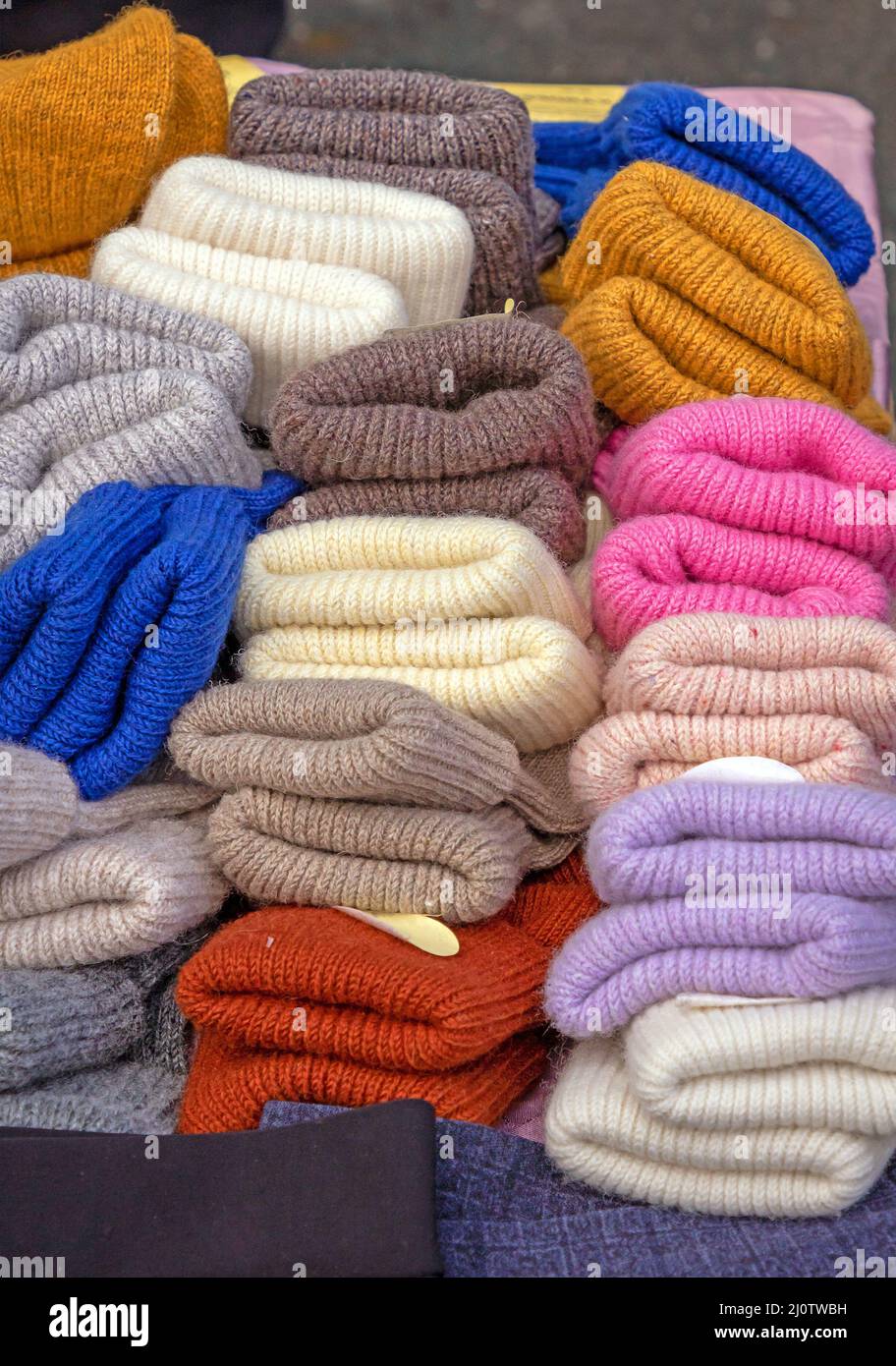 Colorful warm wool gloves pile sold on market stall Stock Photo