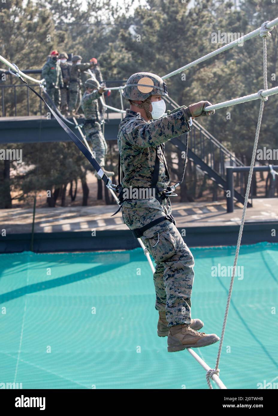 U.S. Marine Corps Sgt. Donovan Hage, a tactics instructor with 3D Sustainment Group (Experimental), 3D Marine Logistics Group, right, crosses a rope bridge during a ropes course with U.S. Marine Corps Forces Korea and Republic of Korea Marine Corps Ranger School in Pohang, South Korea, Jan. 27, 2022. The course increased the Marines’ readiness with rappelling and rope work while improving interoperability with our partners and allies. (U.S. Marine Corps photo by Sgt. Ash McLaughlin) Stock Photo