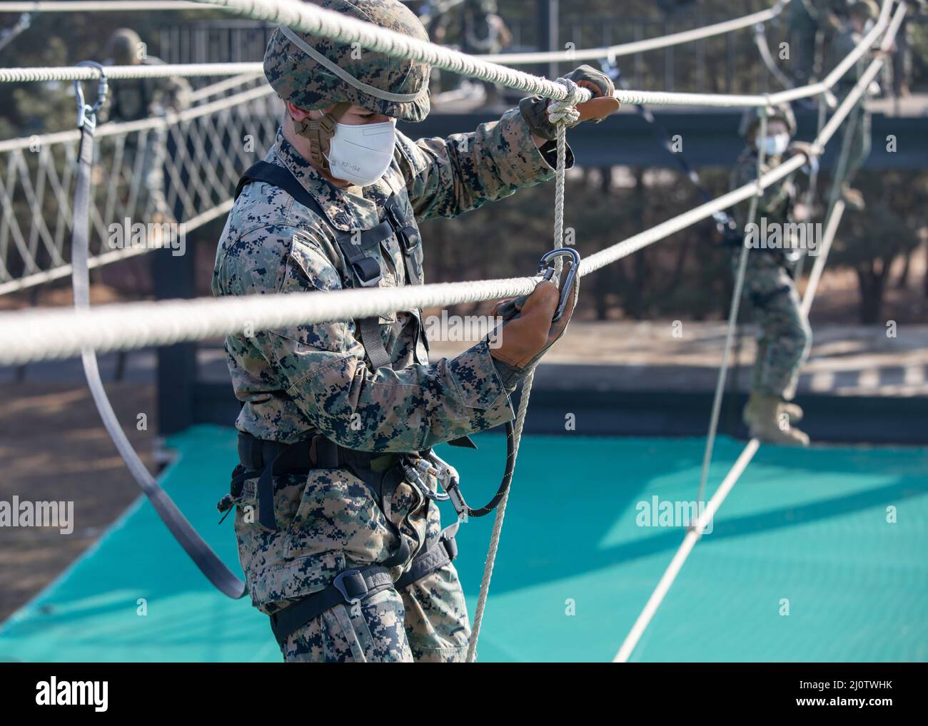 U.S. Marine Corps Sgt. Erick Ortizmiller, an intelligence specialist with U.S. Marine Corps Forces Korea, left, secures his carabiner to the rope bridge during a ropes course with and 3D Sustainment Group (Experimental), 3D Marine Logistics Group and Republic of Korea Marine Corps Ranger School in Pohang, South Korea, Jan. 27, 2022. The course increased the Marines’ readiness with rappelling and rope work while improving interoperability with our partners and allies. (U.S. Marine Corps photo by Sgt. Ash McLaughlin) Stock Photo