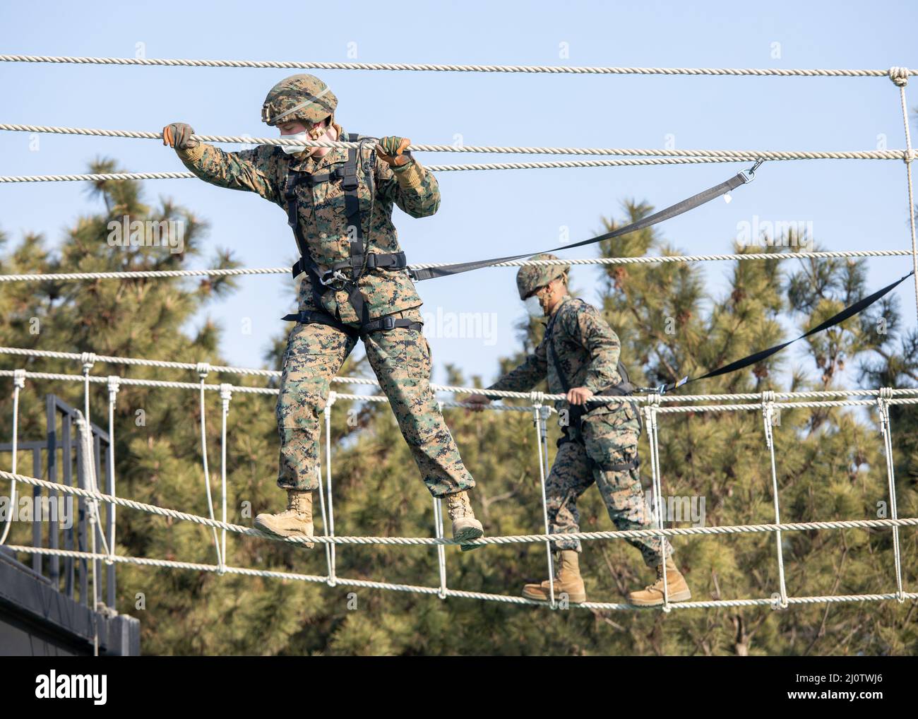 U.S. Marine Corps Lance Cpl. Gunnar Cain, an engineer equipment operator with 3D Sustainment Group (Experimental), 3D Marine Logistics Group, left, and Cpl. Dominic Bishop, a small arms repair technician with U.S. Marine Corps Forces Korea, cross rope bridges during a ropes course with Republic of Korea Marine Corps Ranger School in Pohang, South Korea, Jan. 27, 2022. The course increased the Marines’ readiness with rappelling and rope work while improving interoperability with our partners and allies. (U.S. Marine Corps photo by Sgt. Ash McLaughlin) Stock Photo
