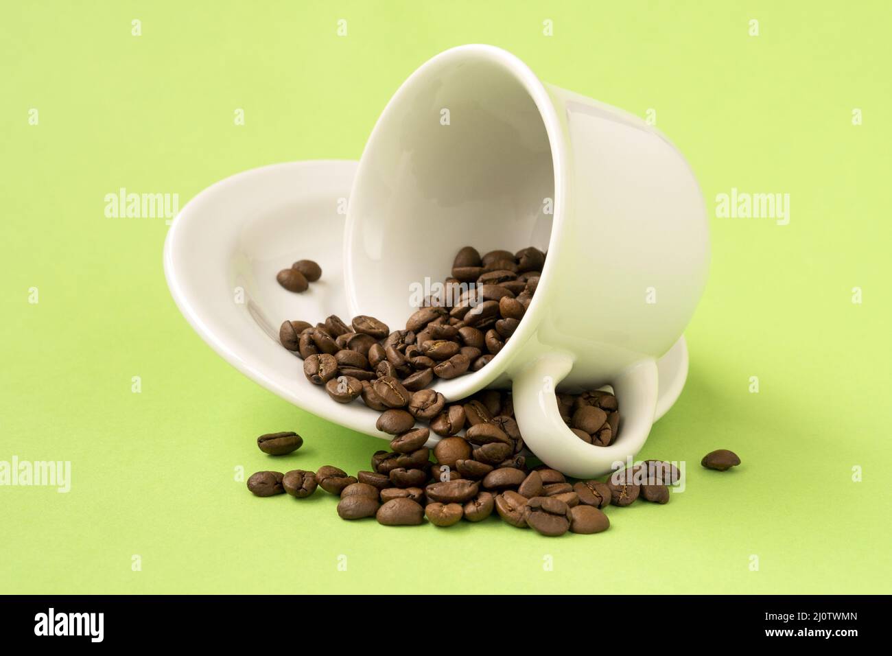 White cup with coffee beans falling on a green background Stock Photo ...