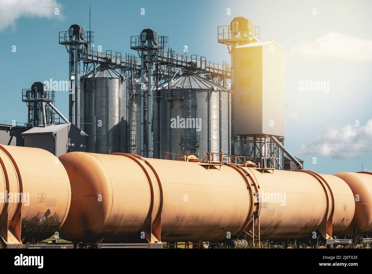 Grain silo, warehouse or depository next to railroad tracks with set of train tanks Stock Photo