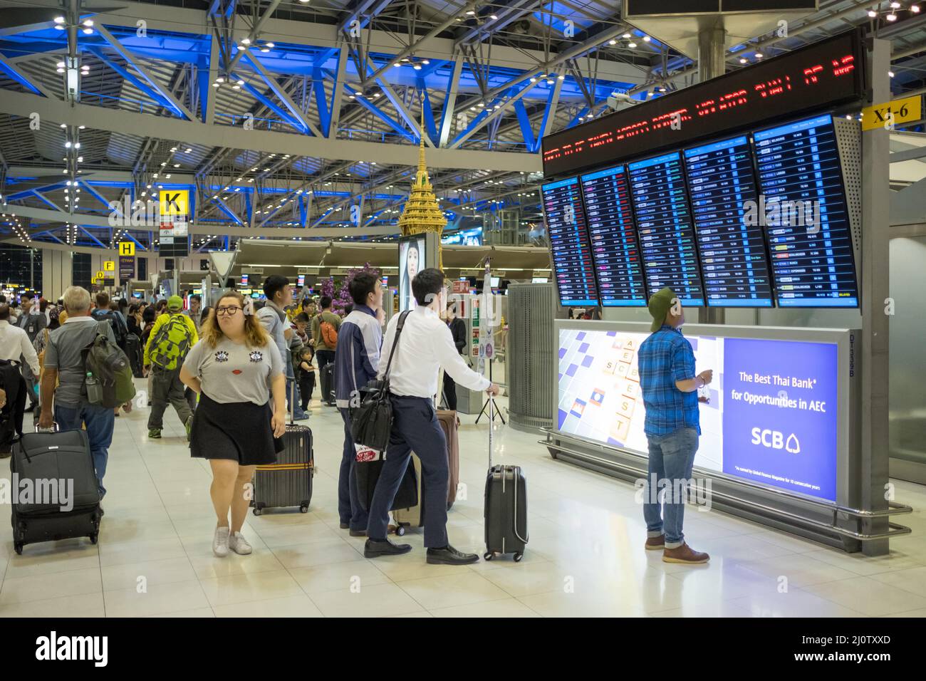 Travelers checking departures at Suvarnabhumi Airport in Bangkok. This is one of the busiest airports in the world. Stock Photo