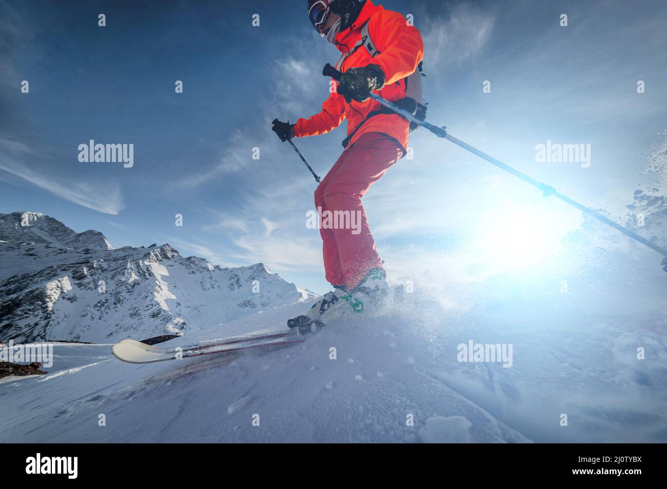 Close up Skier rides on a snowy slope on a sunny day at sunset against ...