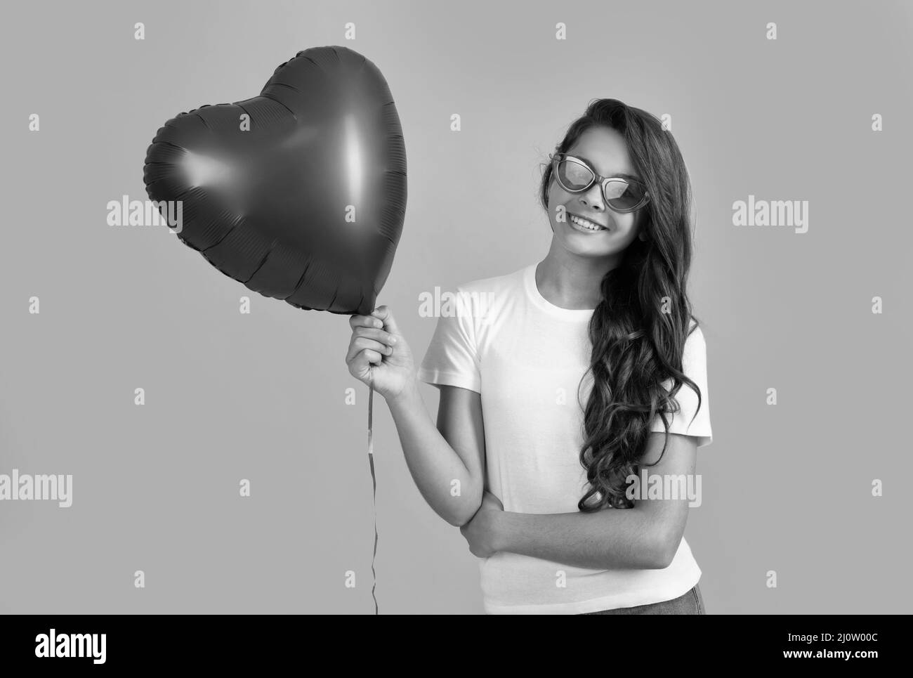 happy teen girl in sunglasses hold heart party balloon for valentine day love symbol, romantic party Stock Photo